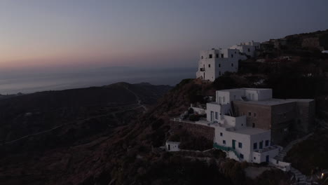 Perspectiva-Aérea-Del-Pequeño-Pueblo-En-La-Isla-De-Milos,-Grecia-Después-Del-Atardecer-Con-Vista-Al-Mar