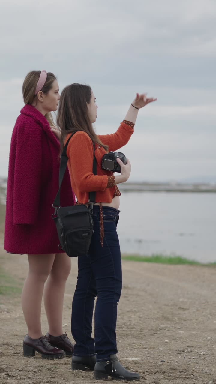 Two women on a coastal walk taking photographs