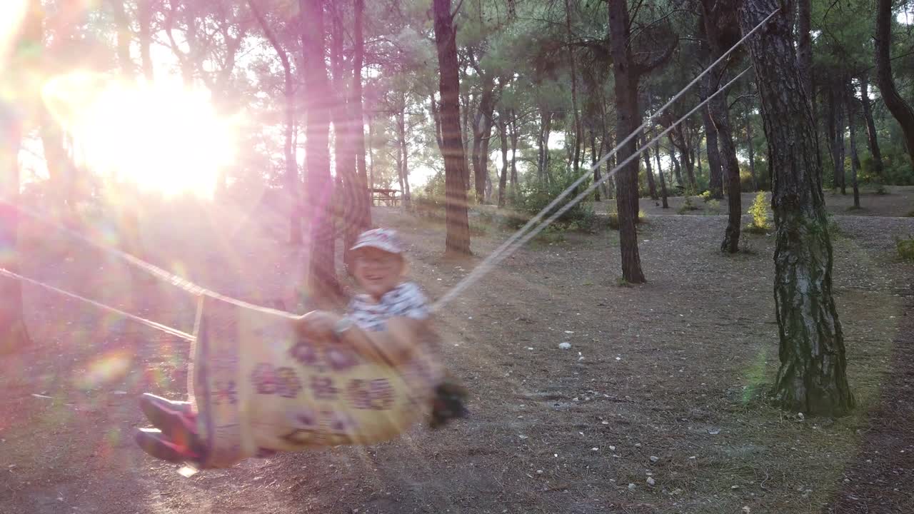 a girl is swinging at the forest with lens flare from picnics