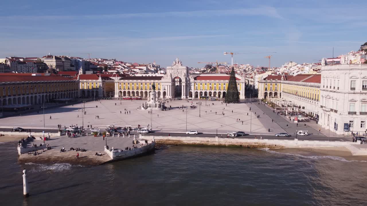 Drone che vola vicino all'Arco da Rua Augusta dalla baia sul mare con persone e un albero di Natale a Lisbona, Portogallo, Europa.