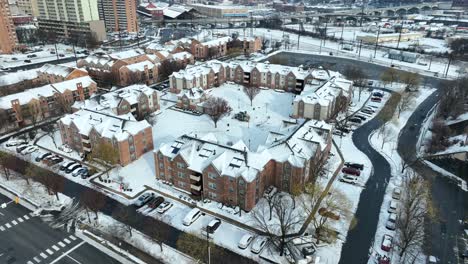 snow-covered residential complex with brick buildings and parked cars, urban backdrop