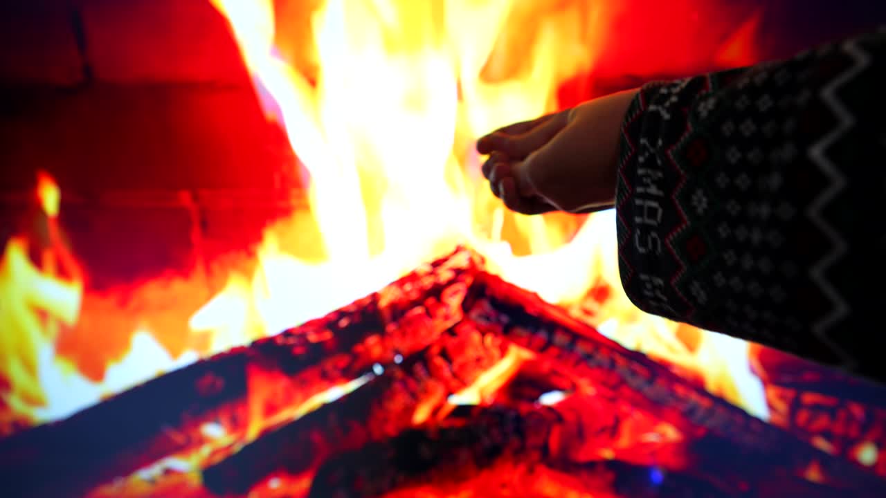mujer en pijama de navidad calentando las manos en la chimenea en una pantalla