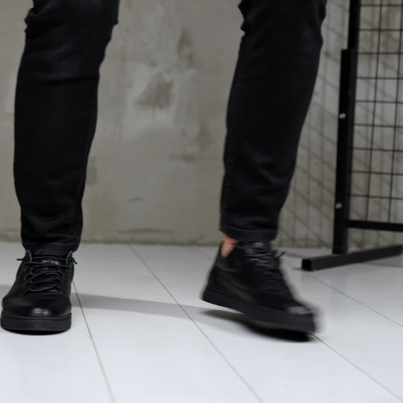 Male model moving and dancing in the studio. Cropped image of a man demonstrating comfortable black leather sport shoes