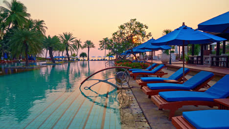 piscina de cama y sombrilla alrededor de la piscina con cielo de puesta de sol o amanecer