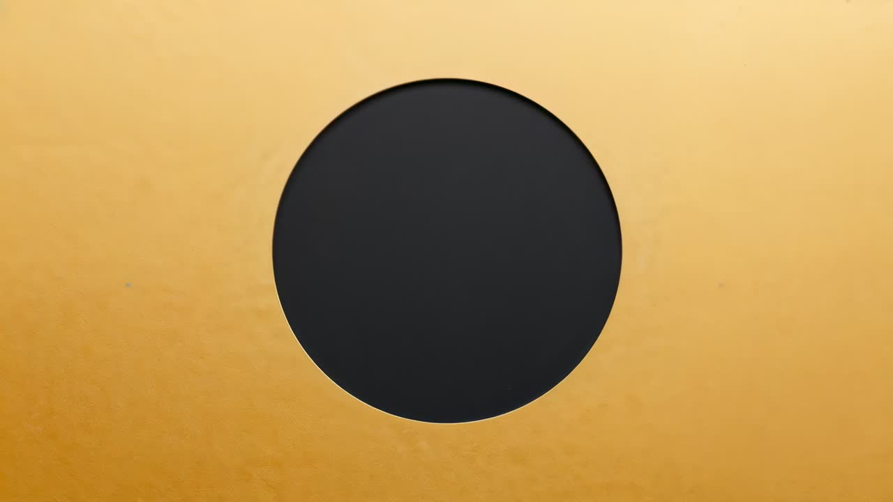 Expanding black cutout sliding down as frames run on gold panel, showing beveled rim, marks, light