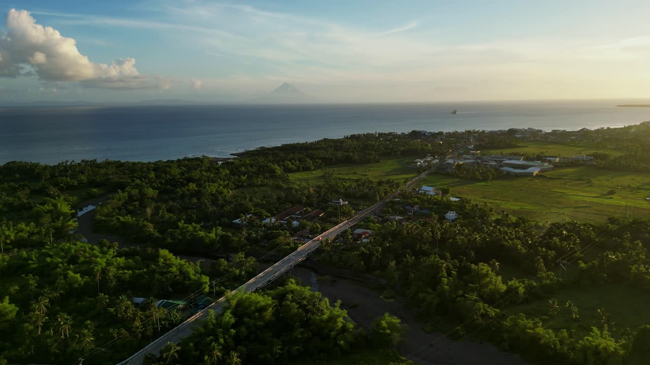 Scenic overhead drone shot of province highway road amid lush tropical island greenery and coastal villages - San Andres, Catanduanes, Philippines
