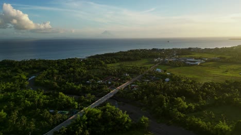 scenic overhead drone shot of province highway road amid lush tropical island greenery and coastal villages - san andres, catanduanes, philippines