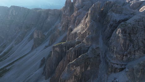 aerial drone capture of the dolomites showcasing rugged rock walls with the sun's rays highlighting their intricate textures and formations