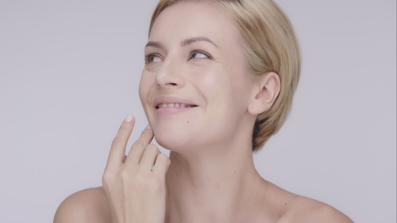Beautiful healthy woman touching smooth skin on face in slow motion for beauty skincare concept on a grey background Red Epic Dragon