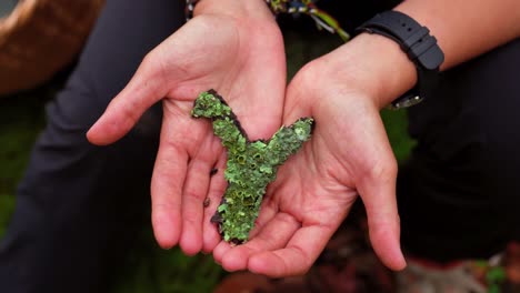 Woman-showing-lichen-in-hands-in-forest