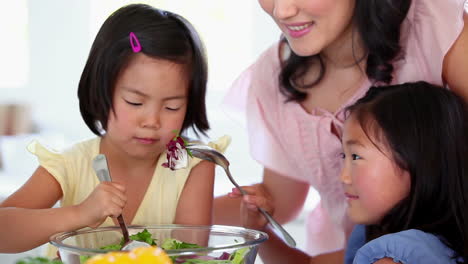 daughters mixing a salad with their mother