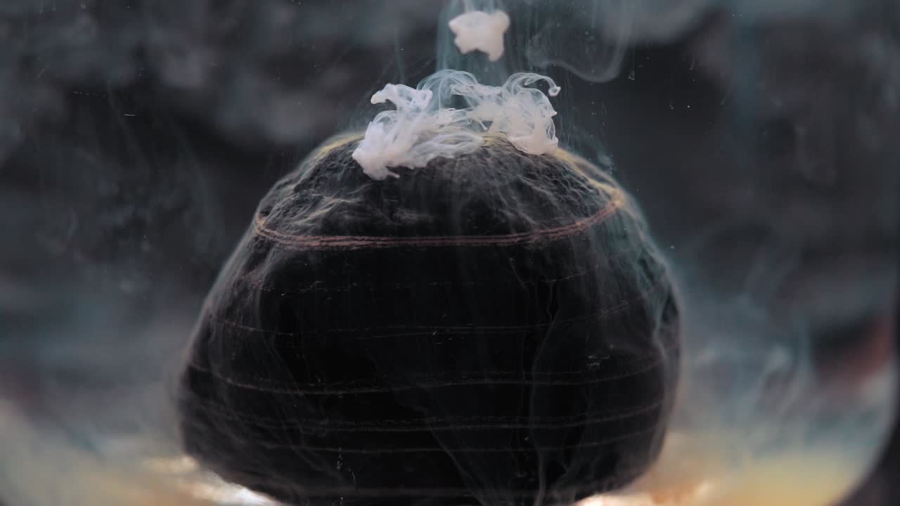 White paint falling on layered rock inside water tank. Slowmotion, stable shot with the Sony a7iii.