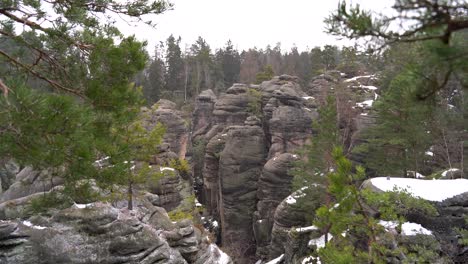 outlook on a sandstone rock formation through branches in prachov rocks, bohemian paradise, in winter, tilt up