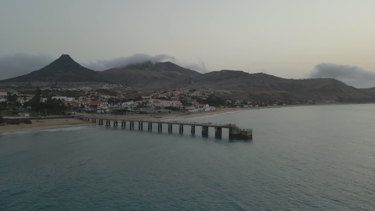 drone panea sobre un muelle mientras las nubes grises ruedan sobre las montañas en la mañana