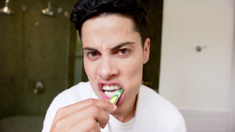 Focused-biracial-man-brushing-teeth-in-morning,-reflected-in-bathroom-mirror,-slow-motion