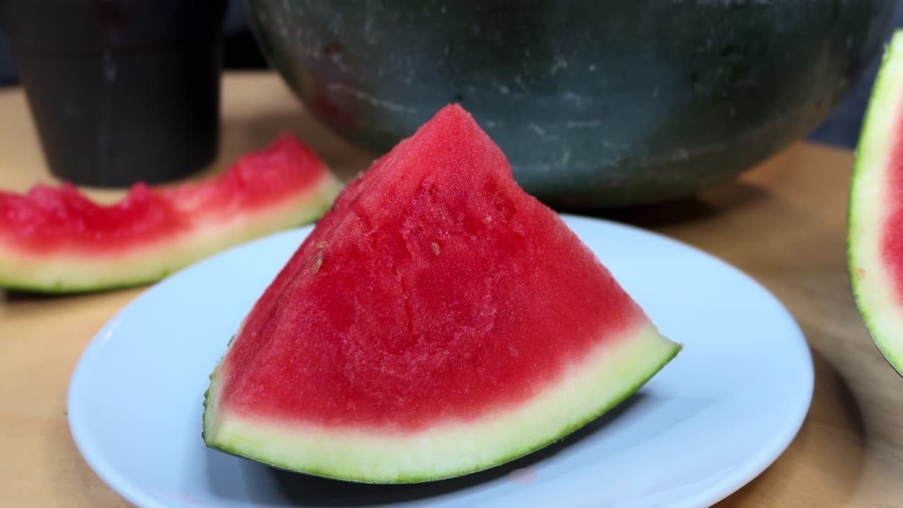 Close-up of a juicy red watermelon slice on a plate, perfect for summer, food, health, and lifestyle projects. Fresh tropical fruit footage for creative use