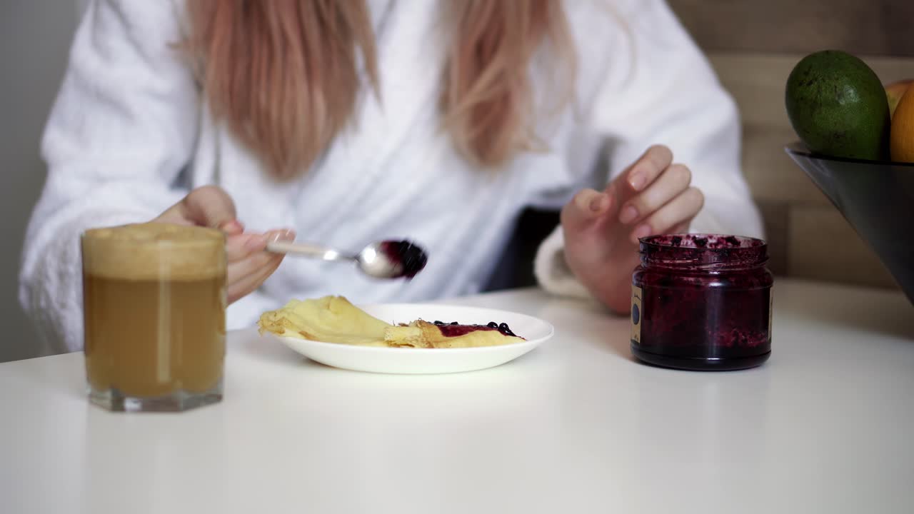 Woman has breakfast pancakes with berry jam and fresh apple juice at home