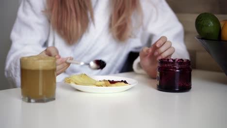 Woman-has-breakfast-pancakes-with-berry-jam-and-fresh-apple-juice-at-home