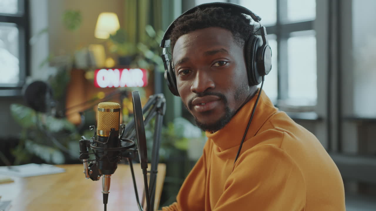 retrato de un hombre negro feliz con auriculares en un estudio de grabación de podcast