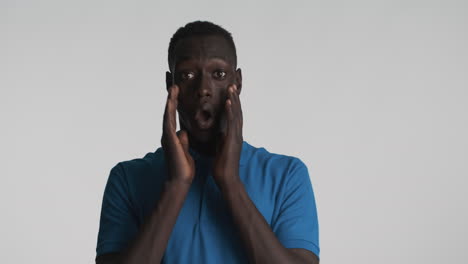 sorprendido hombre afroamericano en fondo gris.
