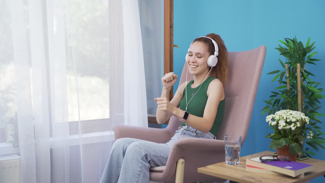 여자가 창밖을 바라보고 헤드폰으로 음악을 듣고 있습니다.