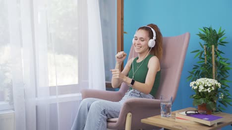 woman looking out the window and listening to music with headphones.