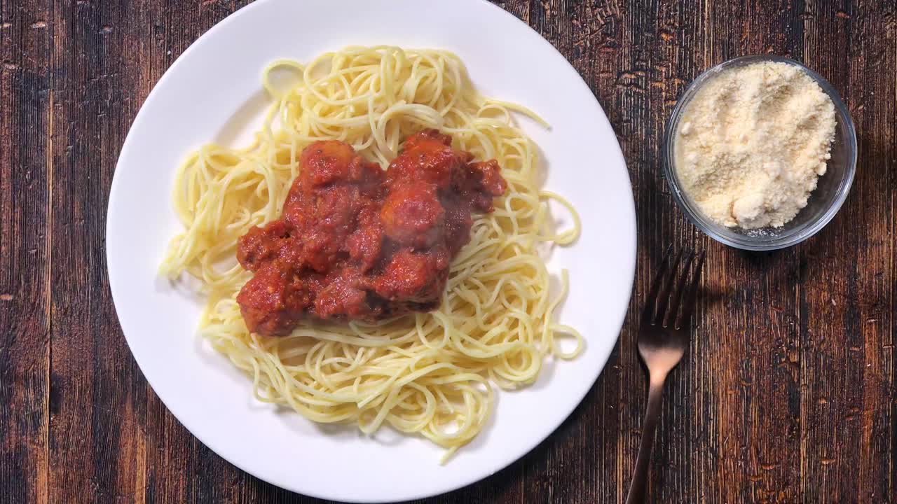 수제 미트볼과 스파게티 소스를 국수 위에 추가하고 파마산 치즈를 위에 추가하는 국자의 오버헤드 뷰