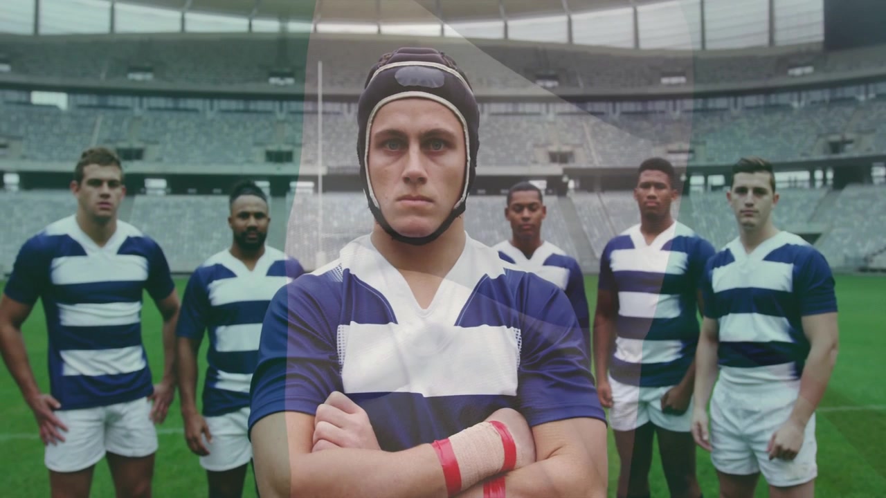Capitano di rugby in piedi al centro mentre i compagni di squadra entrano nell'inquadratura sul campo, preparandosi per un calcio d'inizio dinamico.