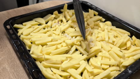la adición de queso con prensa de mano en la parte superior de las patatas crudas en julienne cortadas para hornear