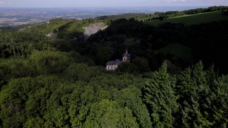 Aerial-view-of-a-chatea-in-the-middle-of-a-forest,-the-clouds-pass-and-cover-the-sun,-we-see-the-forest-darken