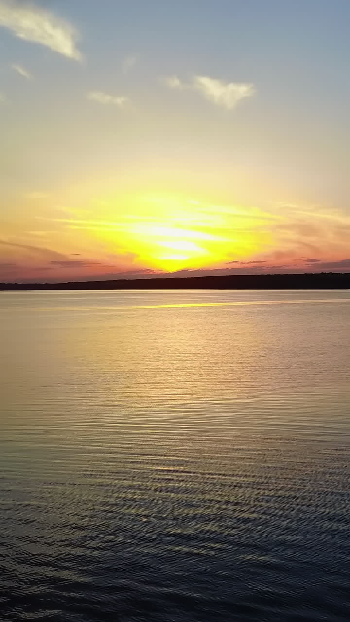 Young People Near River At Sunset. Silhouettes of young people watching on the water of river at sunset Vertical video