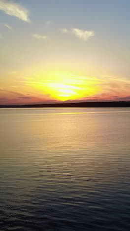 young people near river at sunset. silhouettes of young people watching on the water of river at sunset vertical video