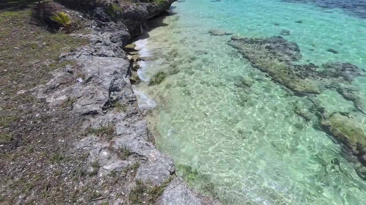 Acqua oceanica cristallina e turchese che lambisce una costa tropicale rocciosa
