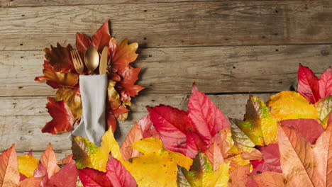 animation of autumn leaves over thanksgiving dinner place setting background