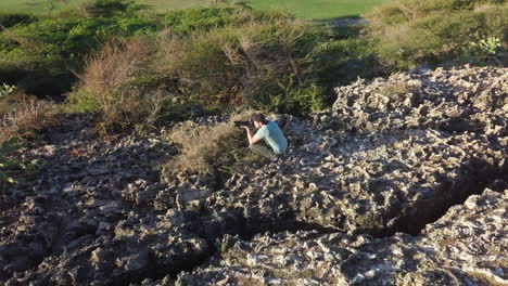 Un-Fotógrafo-De-Vida-Silvestre-Escondido-Detrás-De-Arbustos-De-Cactus-Para-Tomar-Fotos-De-Cabras-Salvajes-En-Aruba