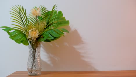 Bouquet-with-monstera-leaves-and-white-flowers-in-vase,-white-background