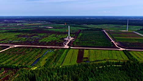 Crane building single wind turbine in vast fields with path cutting through landscape