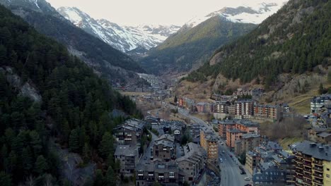 Drone-Aéreo-Asciende-Sobre-Chalets-De-Esquí-En-Valle-Montañoso-Durante-El-Frío-Invierno