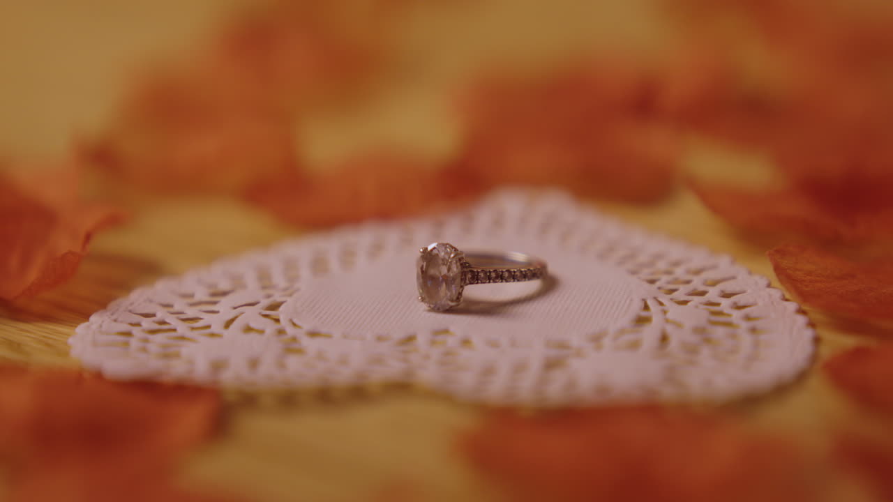 Elegante anello di diamanti su centrino di pizzo con petali arancioni