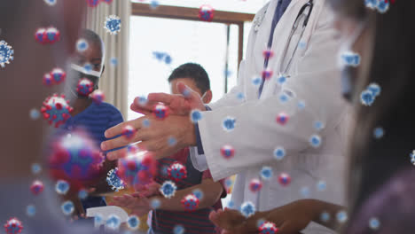 Animation-of-falling-covid-19-cells-over-caucasian-male-doctor-showing-hand-washing-to-children