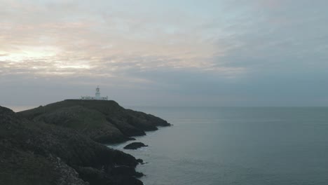 wide view of lighthouse above sea on cloudy evening