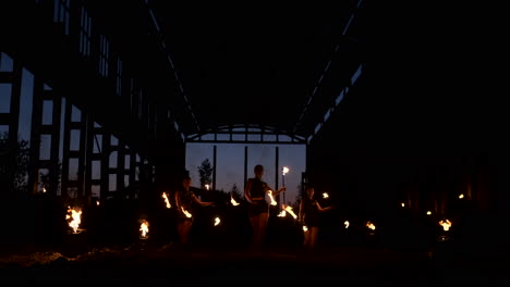 cámara lenta: espectáculo de fuego en el hangar muestra a tres mujeres artistas y un hombre con lanzallamas