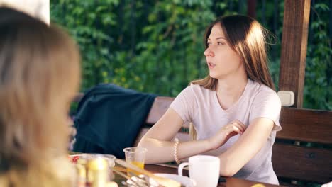 Travelling-CU-Portrait-Two-young-beautiful-girls-are-sitting-in-the-summer-house-talking-smiling