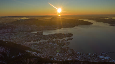hermosa toma aérea que revela la ciudad de bergen debajo de las montañas durante la hora dorada