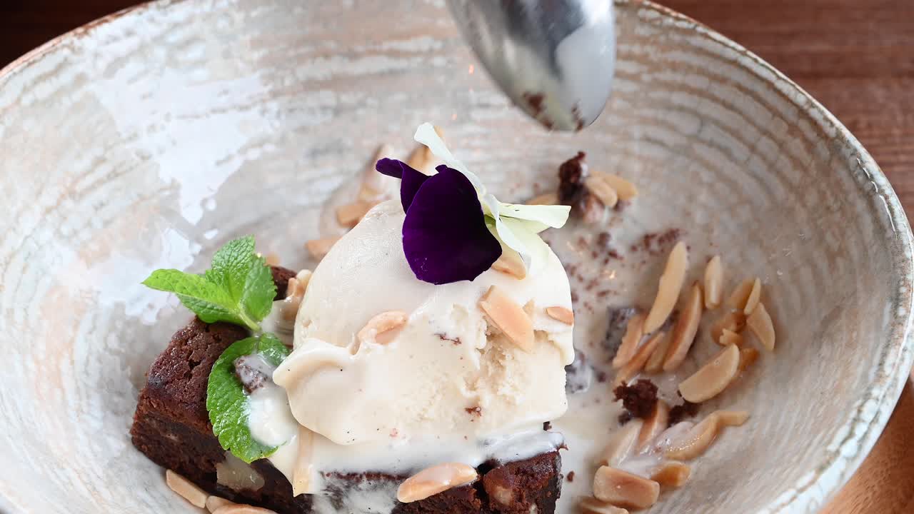 Close up of a woman eating a piece of brownie with vanilla ice cream at a restaurant