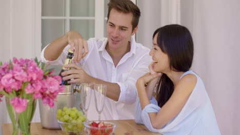 happy young couple opening champagne to drink