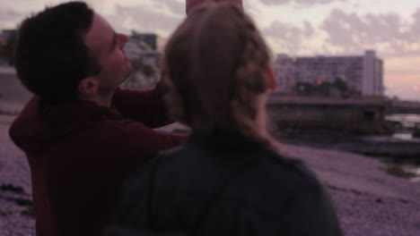 young-couple-sitting-on-beach-talking-casual-enjoying-sunset