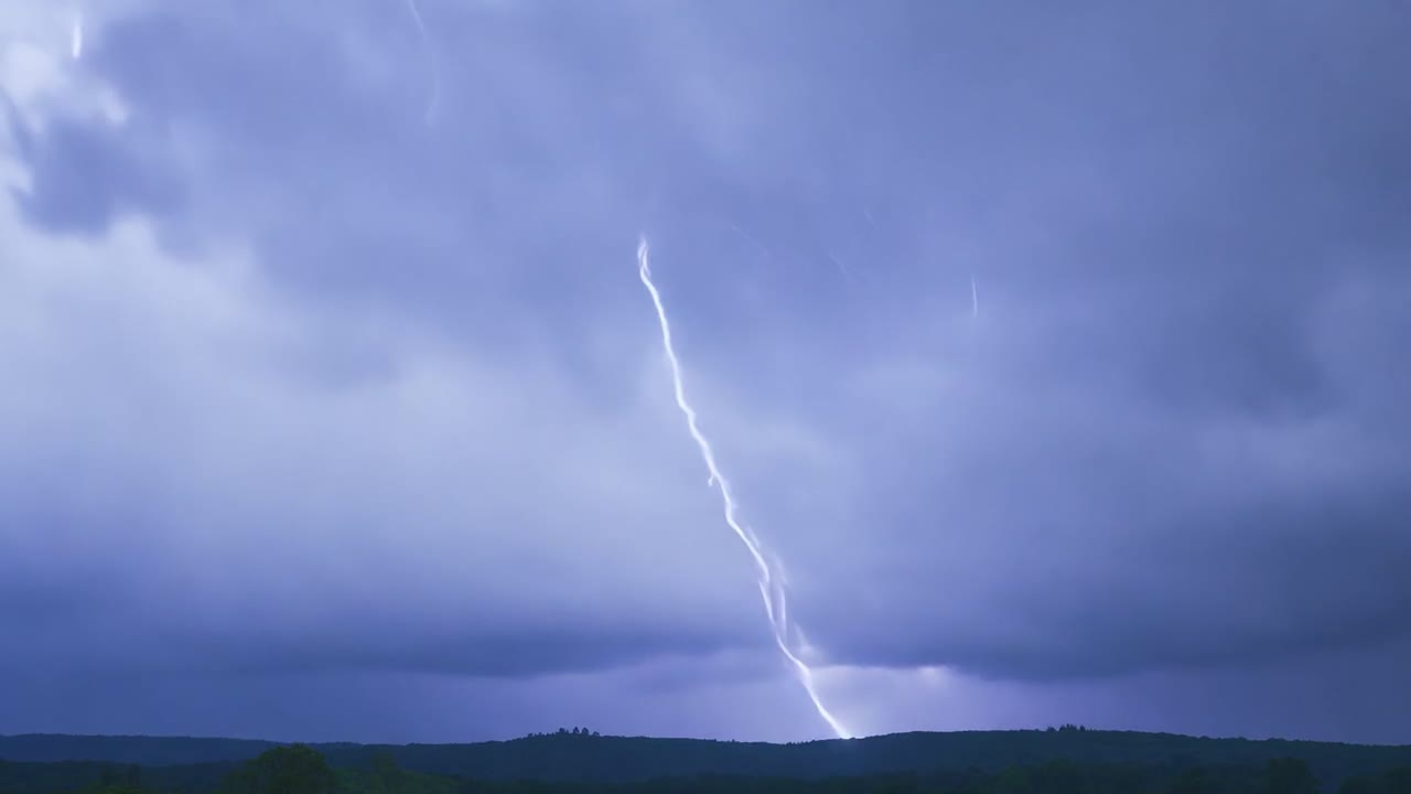 Dramatic stormy sky with bright lightning bolts illuminating rural hills. Captures the power and beauty of natural thunderstorms