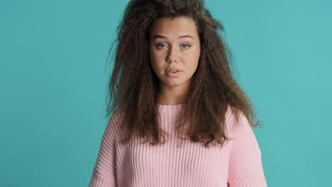 caucasian curly haired woman shrunging shoulders in front of the camera.