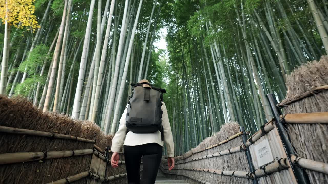 A young woman strolls through the mystical Arashiyama Bamboo Forest in Kyoto, Japan.